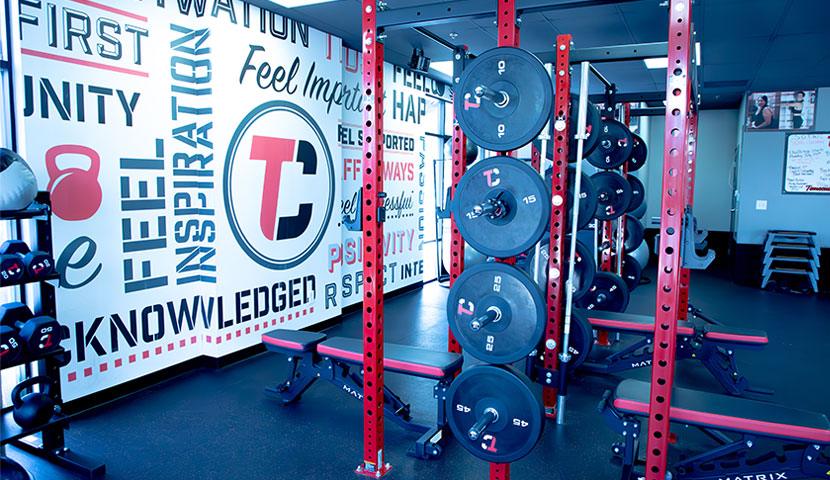 The weight room at The Camp, with squat racks, dumbbells and kettlebells.