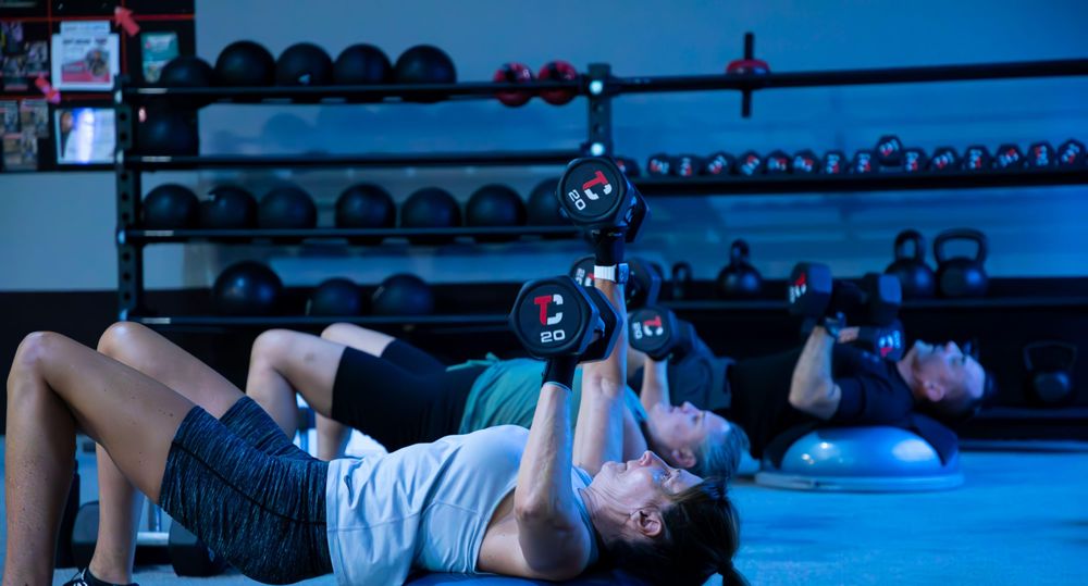A class pressing dumbbells from the floor at The Camp.